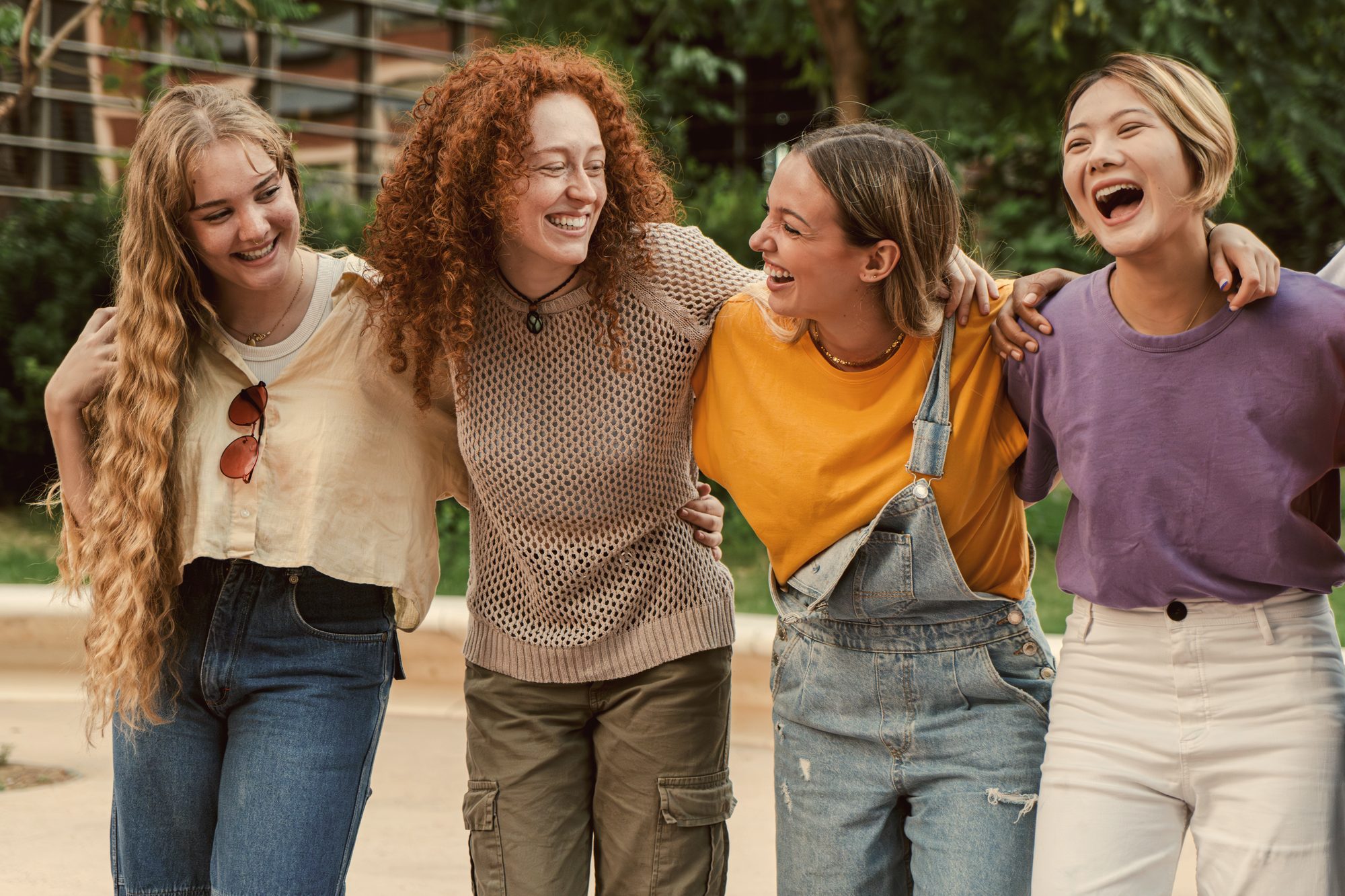 Four young women laughing together, arm in arm