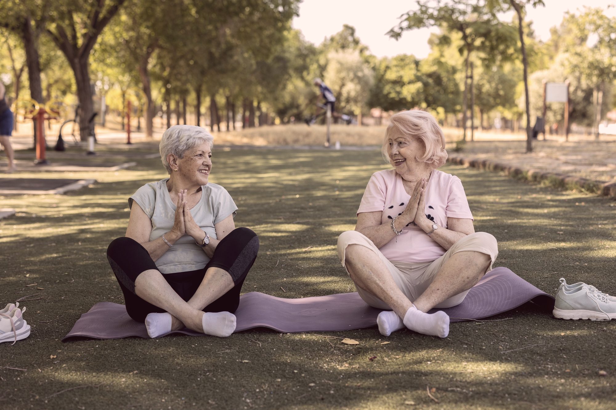 Two senior women doing yoga in the park